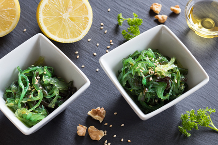 Fresh seaweed salad in two square bowls on a dark backgroundの写真素材