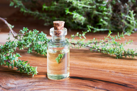 A bottle of thyme essential oil with fresh thyme twigs in the backgroundの写真素材