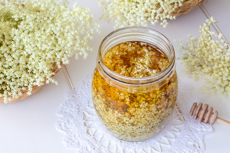 A jar filled with fresh elder flowers and honey, to prepare homemade herbal syrupの写真素材