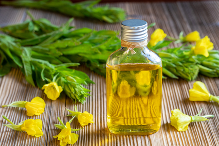 A bottle of evening primrose oil with fresh blooming plant in the backgroundの写真素材