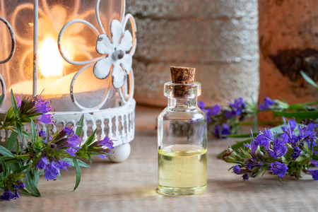 A bottle of essential oil with fresh blooming hyssop and a candleの写真素材