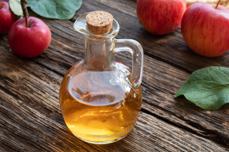 A bottle of apple cider vinegar on a rustic backgroundの写真素材