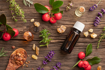 Bottles of essential oil with frankincense, wintergreen, mountain savory and other herbs on a wooden backgroundの写真素材