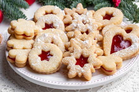 Traditional Linzer Christmas cookies filled with strawberry jam and dusted with sugar on a plateの写真素材