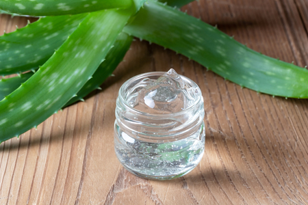 Aloe vera gel in a glass jar and fresh leavesの写真素材