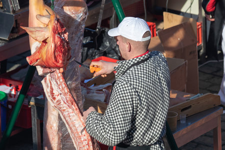 PRAGUE, CZECH REPUBLIC - FEBRUARY 16, 2019: Butcher cutting pork meat at the Naplavka farmers marketのeditorial素材