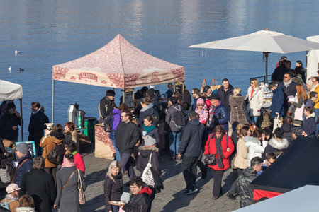 PRAGUE, CZECH REPUBLIC - FEBRUARY 16, 2019: People walking and shopping at the farmers market at the Naplavka riverbank, with the Vltava river in the backgroundのeditorial素材