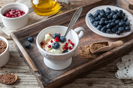 Cottage cheese with ground linseeds, blueberries and frozen cranberries, with red currants and flax seed oil in the backgroundの写真素材