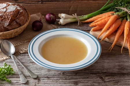 Chicken bone broth with fresh vegetables and sourdough breadの写真素材