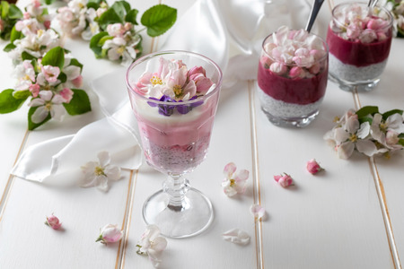 Layered chia pudding with yogurt, red currants, blueberries and apple blossomsの写真素材