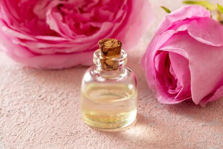 A bottle of essential oil with fresh rose de mai flowers