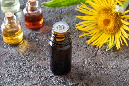 A bottle of elecampane essential oil with blooming Inula helenium plantの写真素材