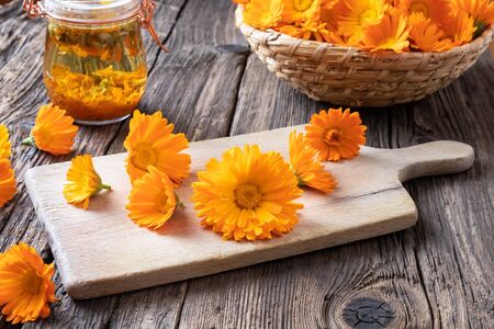 Calendula flowers on a cutting board, with alcohol tincture in the backgroundの写真素材