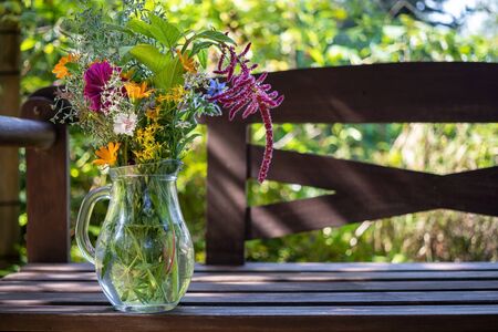 European goldenrod, calendula, mallow and other medicinal herbs in a glass jug in a gardenの写真素材