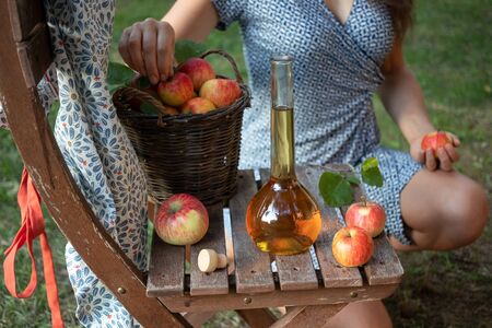 A bottle of apple cider vinegar in a garden, with a woman in the backgroundの写真素材
