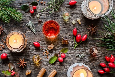 Essential oils on a Christmas background with candles, frankincense, rose hips, wintergreen and other herbsの写真素材