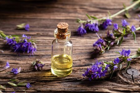 A bottle of essential oil with blooming hyssop twigs on a tableの写真素材