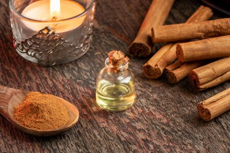 A bottle of essential oil with cinnamon sticks and a candleの写真素材