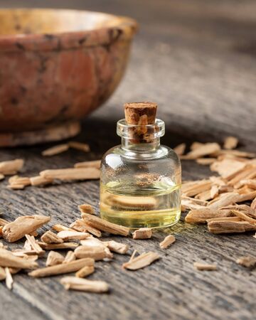 A transparent bottle of essential oil with cedar wood chipsの写真素材