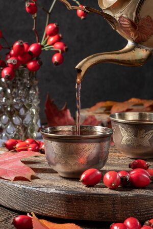 Pouring rose hip tea into a cup