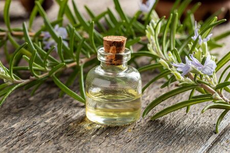 A bottle of essential oil with fresh rosemary leaves and flowersの写真素材