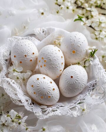 Blown out white Easter eggs decorated with wax, with drilled holesの写真素材