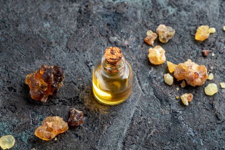 A bottle of essential oil with frankincense resin on a dark backgroundの写真素材