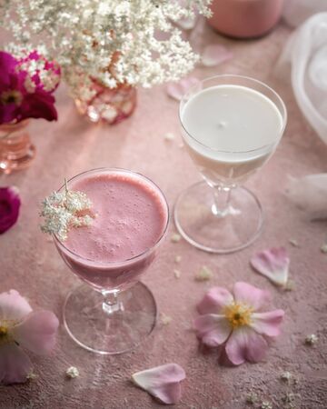A glass of goats milk kefir with blended raspberries on a pink backgroundの写真素材