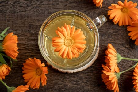 A cup of herbal tea with calendula flowers, top viewの写真素材