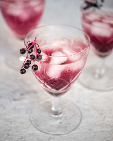 Water with ice and black elder syrup, decorated with elderberriesの写真素材
