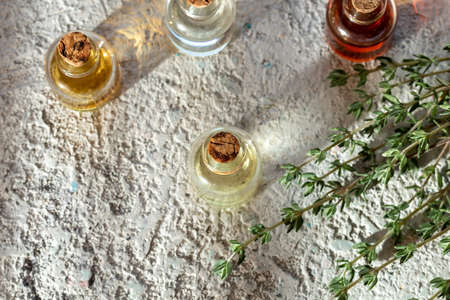 Bottles of essential oil with fresh thyme twigs on a white backgroundの写真素材