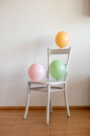 Colorful balloons on a white chair, indoorsの写真素材