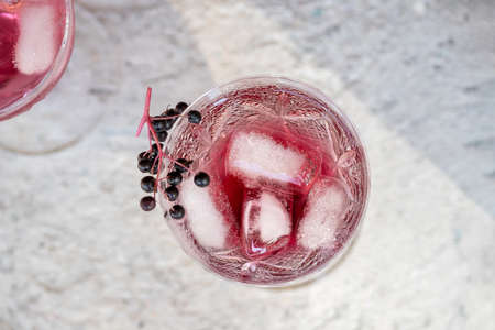 Water with ice and black elder syrup, decorated with elderberries, top viewの写真素材