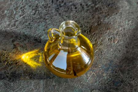 A glass bottle of oil on a dark background