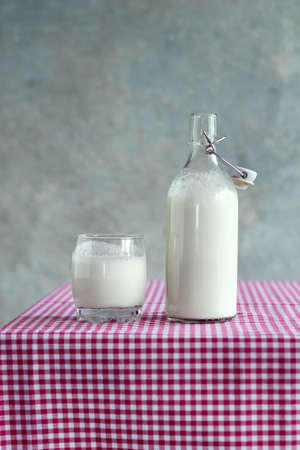 Kefir in a bottle and glass on a red checkered tablecloth