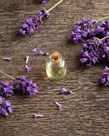 Essential oil bottle with fresh lavender flowers on a wooden background