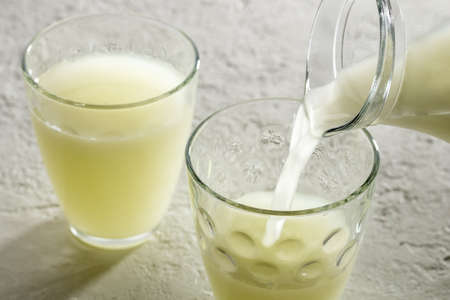 Pouring natural whey from a jug into a glassの写真素材