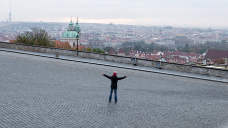 PRAGUE, CZECH REPUBLIC - OCTOBER 19, 2020: Empty Hradcanske Namesti square on a cold autumn morning, with a lonely person stretching out handsのeditorial素材