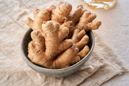 Fresh ginger root in a bowl on a bright backgroundの写真素材