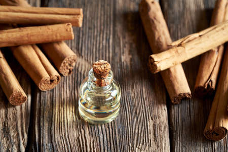 A transparent bottle of essential oil with Ceylon cinnamon sticks on a rustic backgroundの写真素材