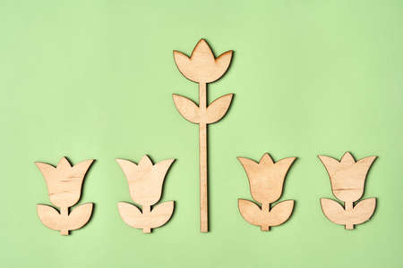 One big wooden flower in the middle of four small ones on green paper background