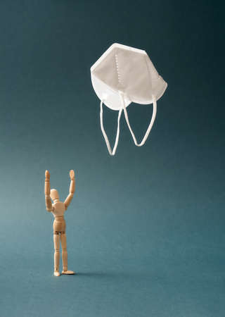 Wooden figure worshipping a white FFP2 or KN95 respiratorの写真素材