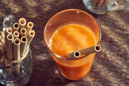 Bamboo straws in a glass of carrot juice on a table - zero-waste concept