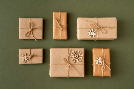 Christmas presents wrapped in ecological recycled paper with wooden decoration on paper background -...