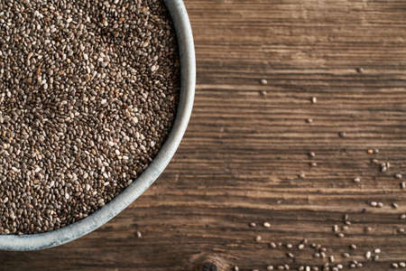 Chia seeds in a bowl, on a wooden background with copy space