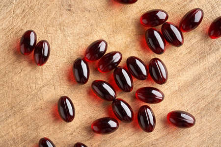 Krill oil pills on a wooden table, top view