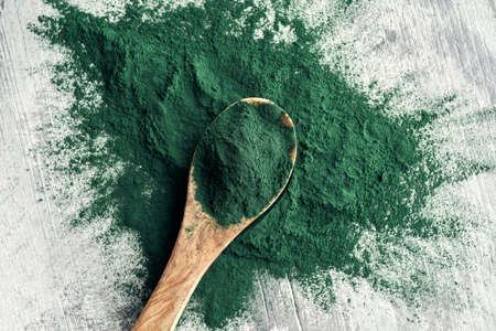 Spirulina powder on a spoon on a table, top viewの写真素材