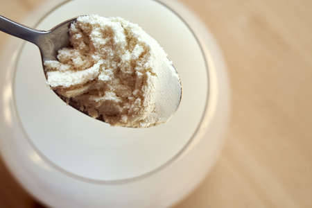 Putting whey protein powder into a glass of water, top viewの写真素材