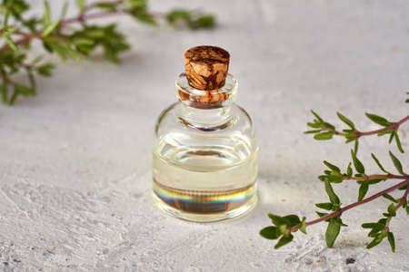 A bottle of essential oil with fresh thyme twigs on white backgroundの写真素材