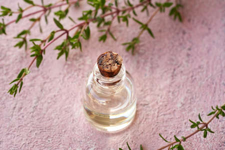 A transparent bottle of essential oil with fresh thyme plantの写真素材